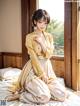 A woman in a yellow kimono sitting on a bed.