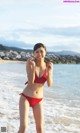 A woman in a red bikini standing on the beach.