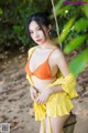 A woman in an orange bikini sitting on a swing.