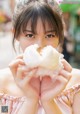 A woman holding a cotton candy in front of her face.