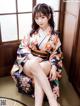 A woman in a kimono sitting on a chair.