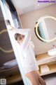 A woman in a white shirt is standing in a bathroom.