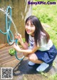 A young woman in a school uniform is holding a hose.