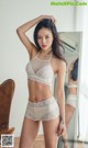 A woman in a white lingerie posing in front of a mirror.