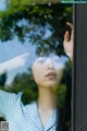 A woman looking out of a window with her hand on her head.