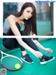 A woman tying up her tennis shoes on a tennis court.