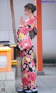 A woman in a kimono standing next to a lantern.