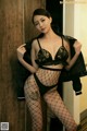 A woman in fishnet stockings leaning against a wall.