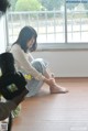 A woman sitting on the floor in front of a window.