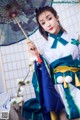 A woman in a blue and green kimono holding an umbrella.