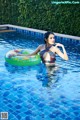 A woman in a bathing suit floating on an inflatable ring in a pool.