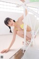 A woman in a yellow bikini is posing on a staircase.